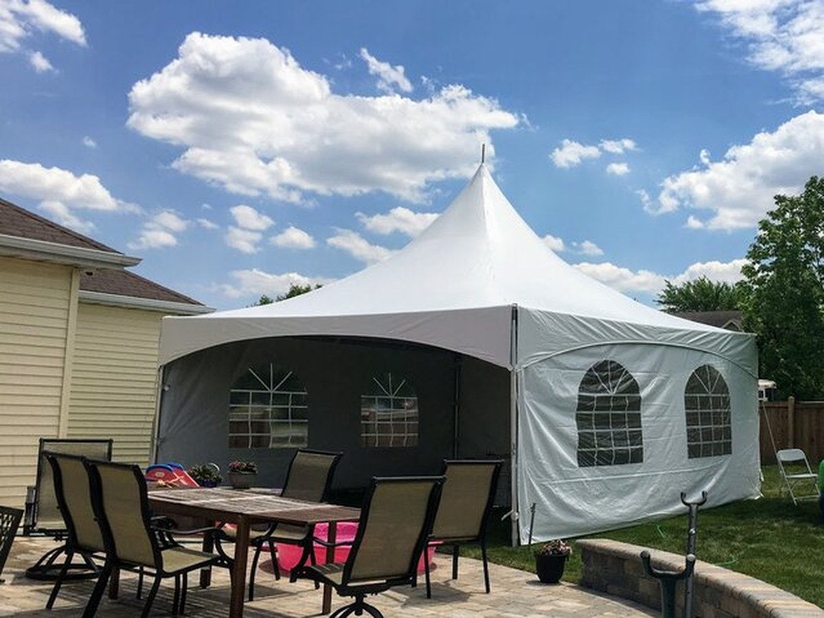 White enclosed event tent in a residential backyard